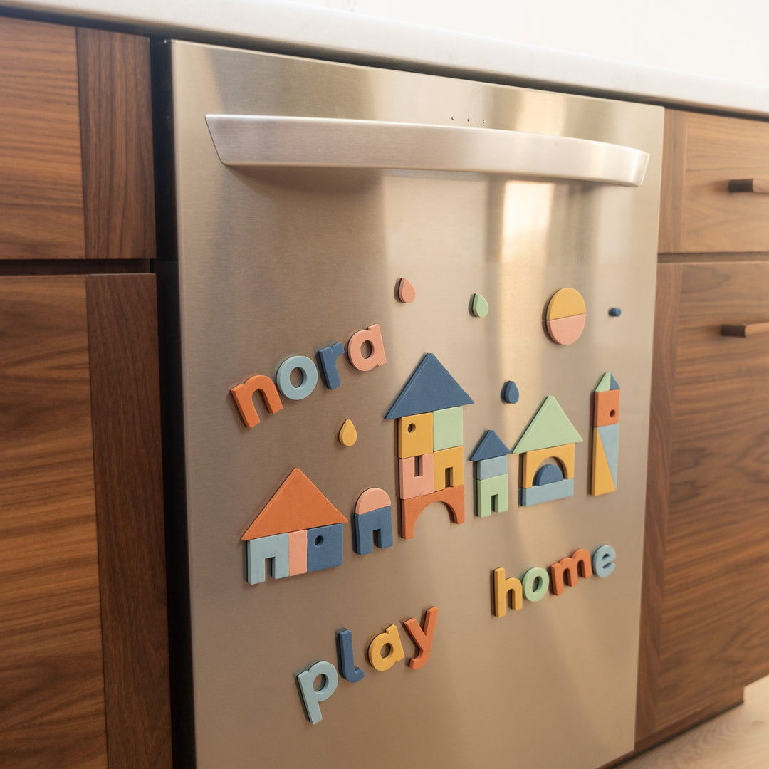 Colorful boho magnetic letters and shapes on a stainless steel dishwasher in a kitchen setting