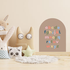 Children's room with plush toys, a star-shaped pillow, and a wall with colorful magnetic letters on small tan magnetic wall decal