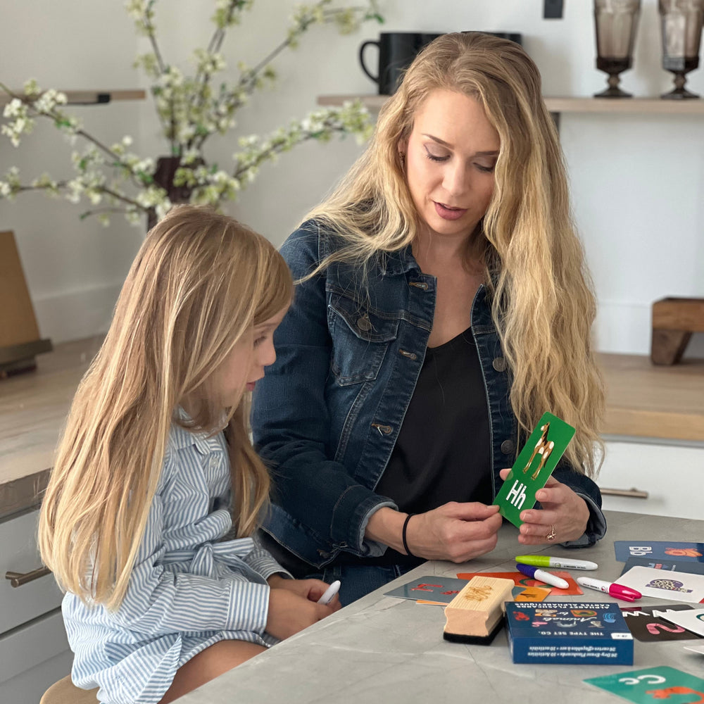 Mom and child using alphabet flashcards together in a kitchen.