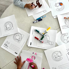 Children coloring printable worksheets with markers on a wooden kitchen tabletop