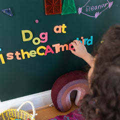 Child playing with colorful magnetic letters on a green magnetic wall decal