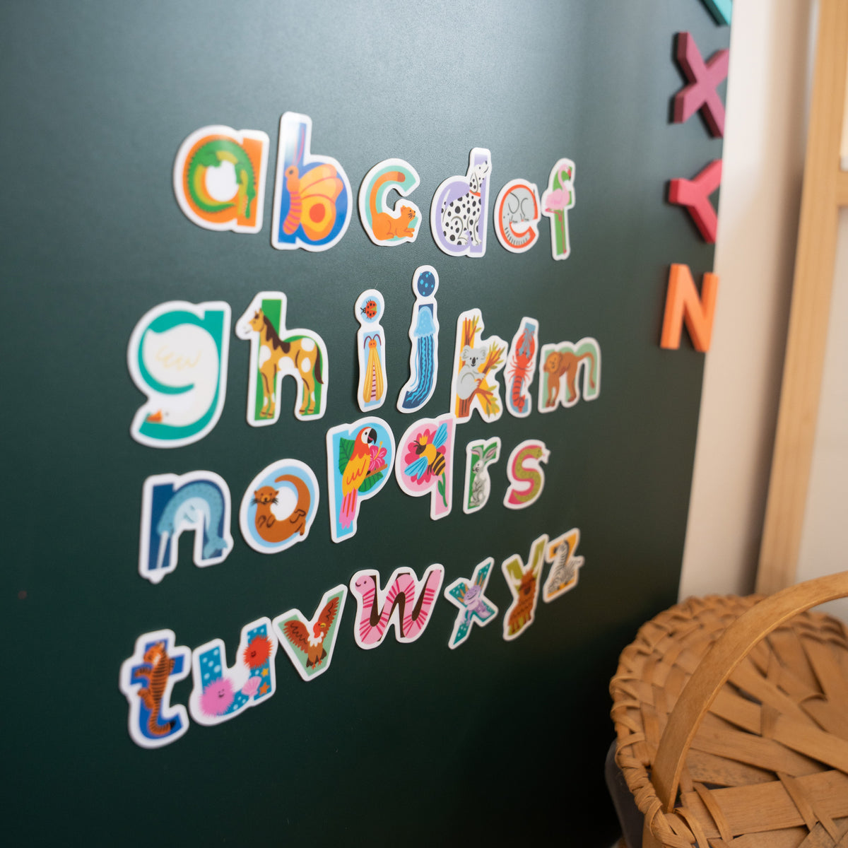 Washable & restickable animal alphabet stickers featured on green magnetic wall decal.