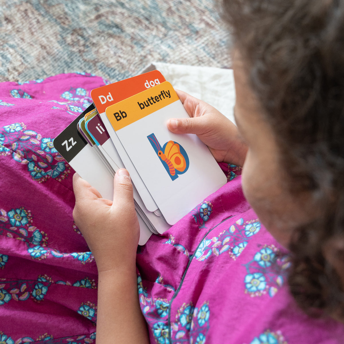 Child holding alphabet flashcards