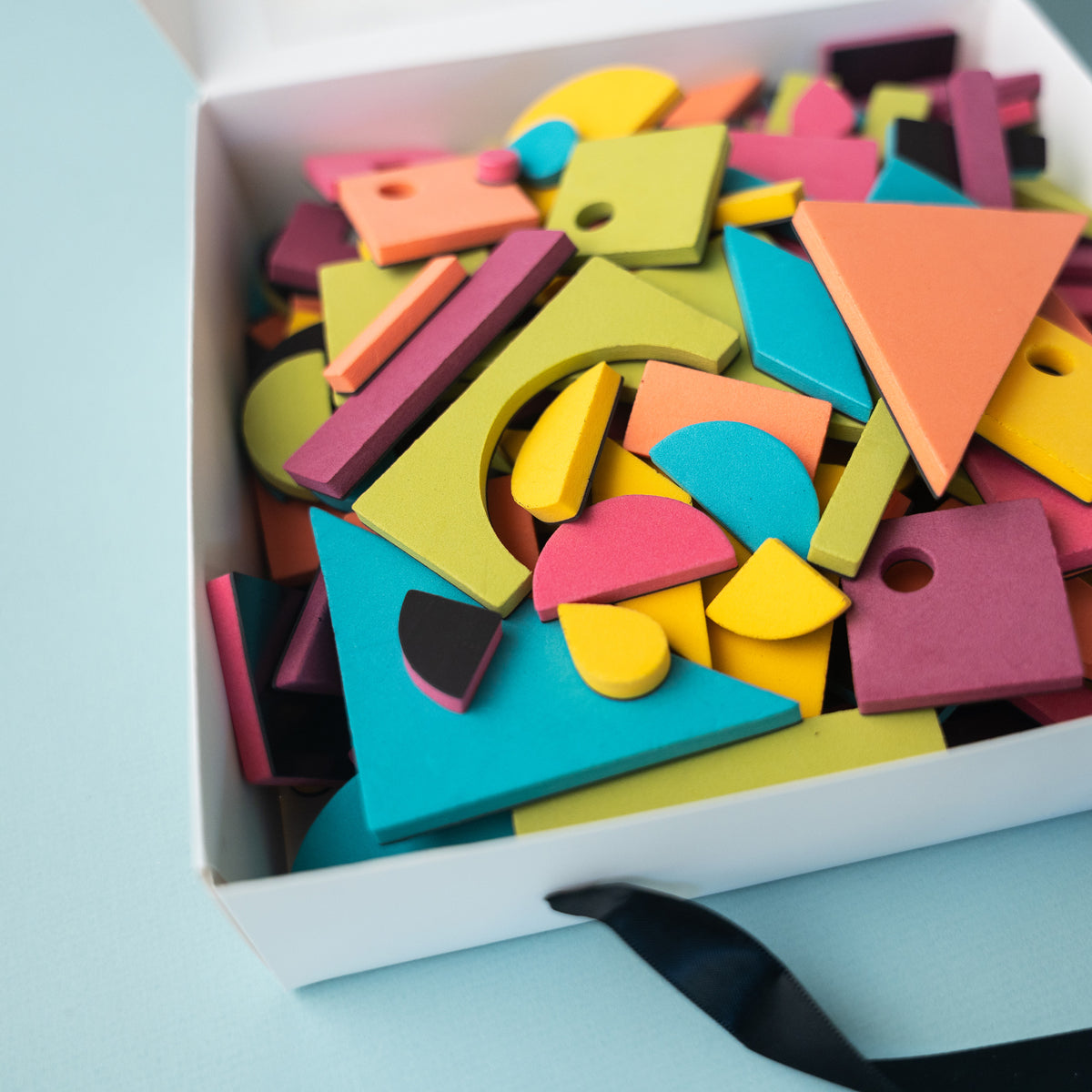 Closeup of foam rainbow pop magnetic shapes set in packaging on light blue background