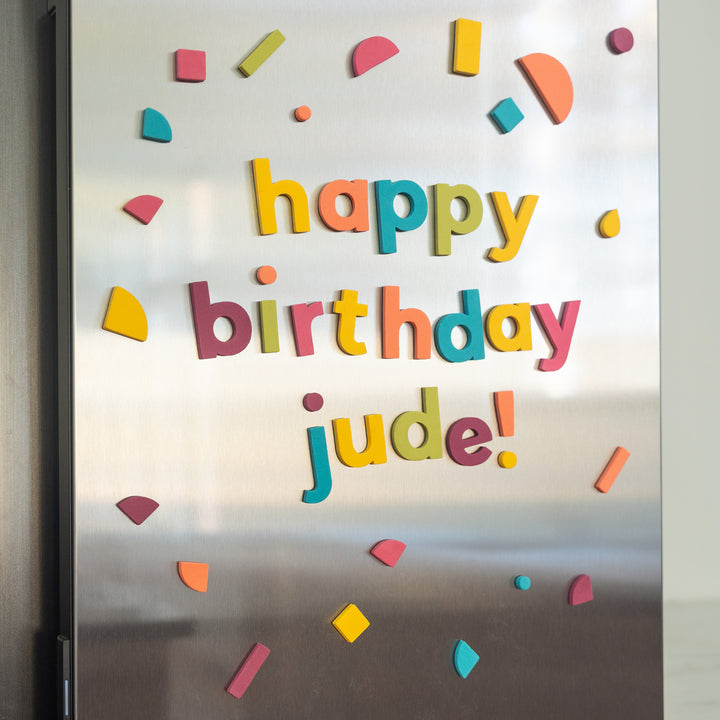 Colorful magnetic letters spelling 'happy birthday jude!' on a refrigerator door.