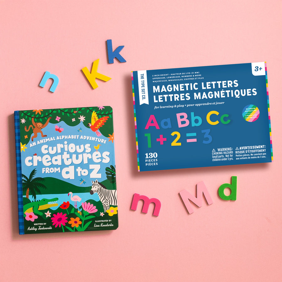 Children's alphabet book and rainbow magnetic letters set on a pink background