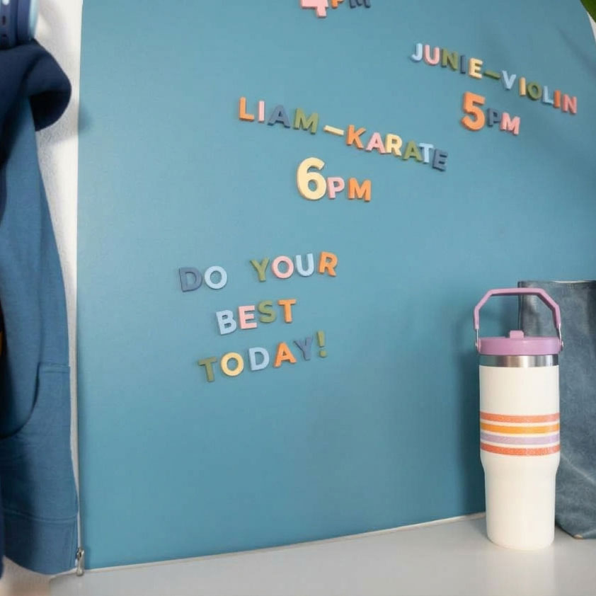 Close up of rainbow alphabet magnets on a medium blue wall decal