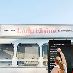 Girl adding white magnetic letters to a mobile bar in an Airstream trailer.