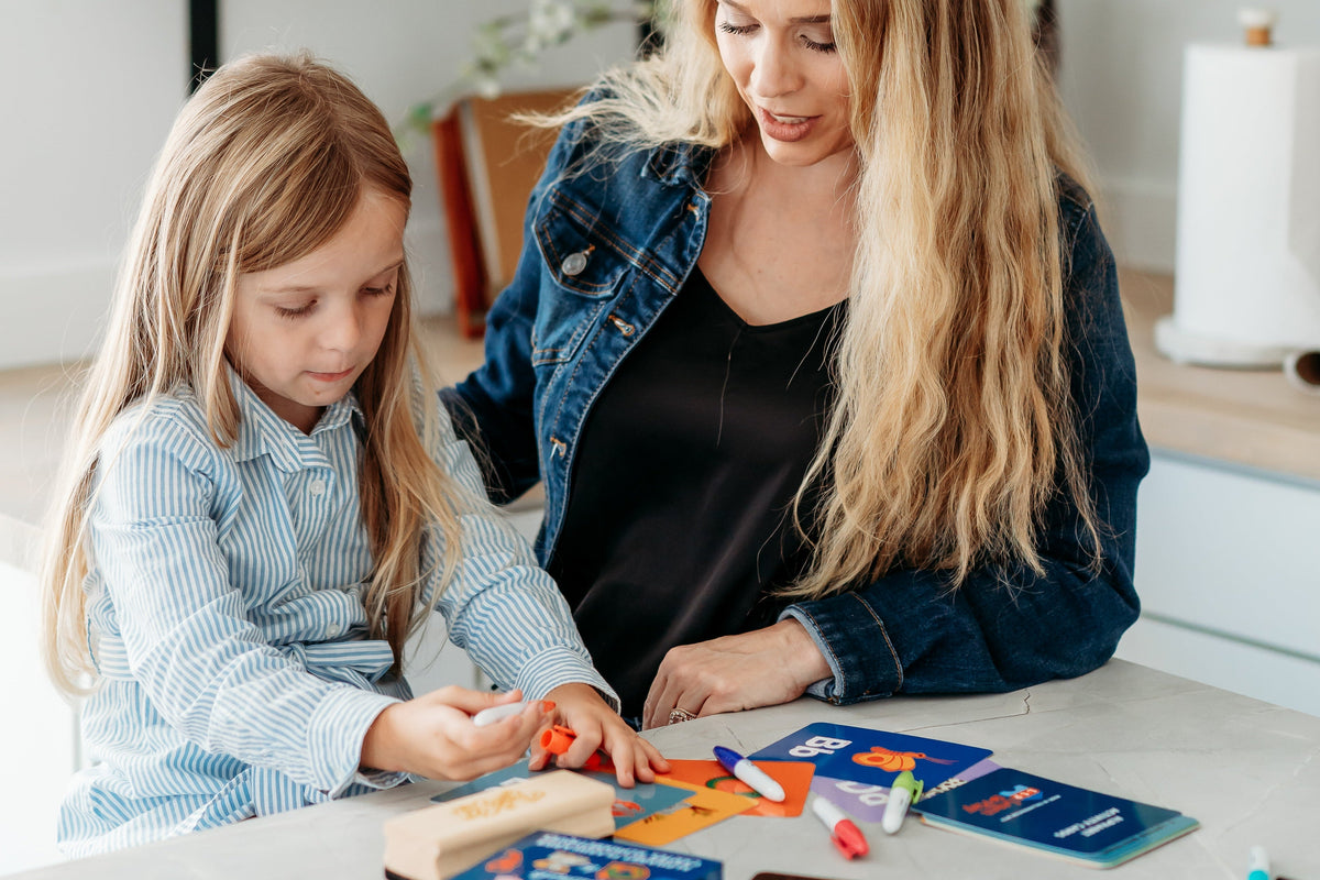 Woman and child playing with alphabet flashcards on a table in a kitchen