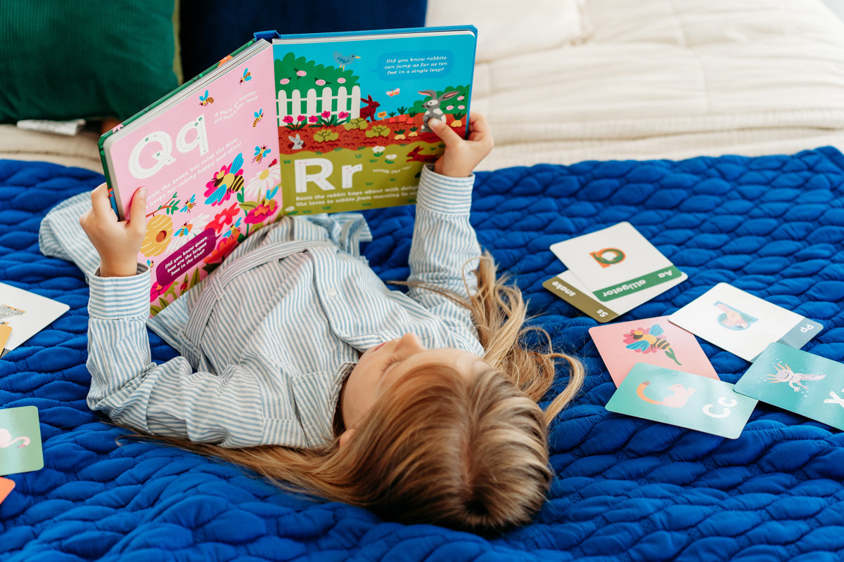 Child reading an alphabet book and playing with letter flashcards.