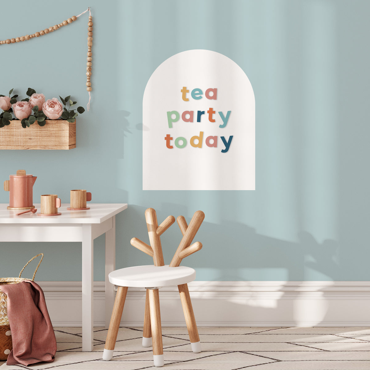 Children's playroom with a 'tea party today' on a white arched magnetic wall decal, table, and chair.